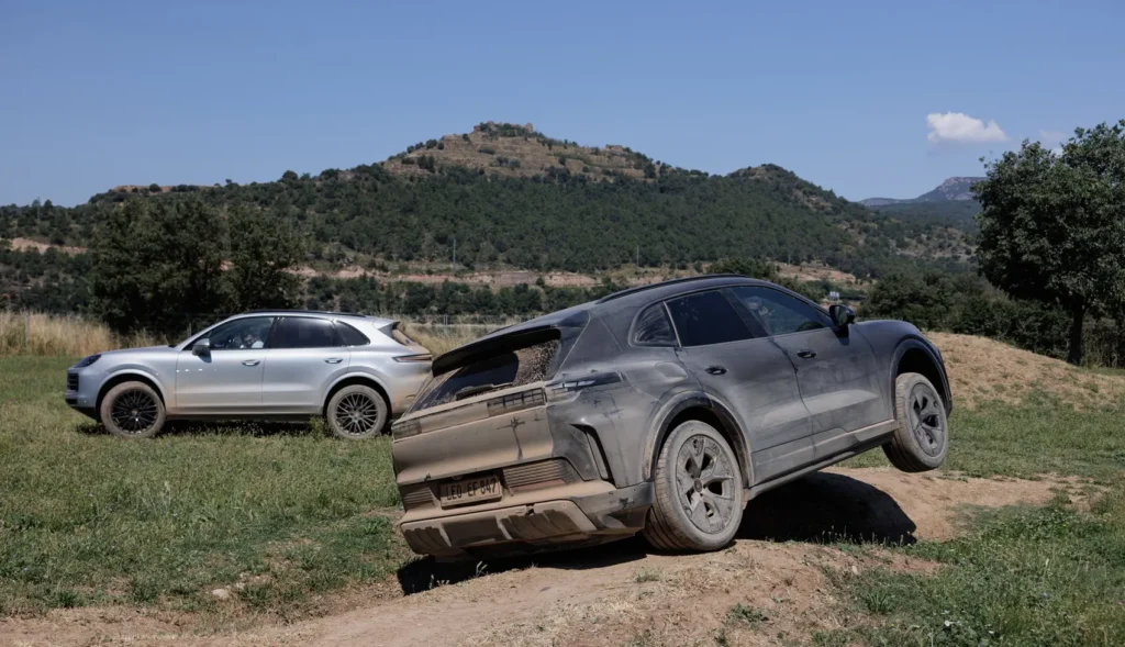 Two 2026-porsche-cayenne-electric-prototype off-roading in nature.